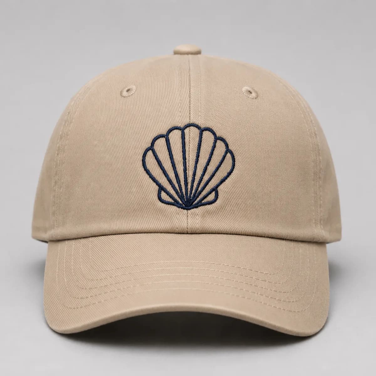 Broderie au point de chaînette sur casquette beige : coquillage en fil marine